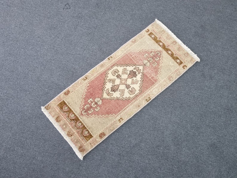 May include: A pink and beige runner rug with a traditional floral pattern. The rug has a fringed edge and is made of wool.