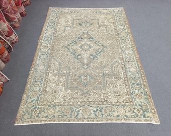 May include: A rectangular, vintage-style rug with an intricate geometric pattern in shades of beige, blue, and brown. The rug features a central medallion design and a border with floral motifs. The rug is displayed on a gray surface.