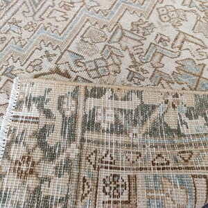 May include: Beige and brown patterned rug with a geometric design. The rug has a distressed look with a mix of light and dark brown, beige, and light blue accents. The edges are fringed.