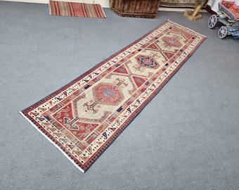 May include: A long, rectangular rug with a traditional Persian design. The rug has a cream background with red, blue, and brown accents. The rug is made of wool and has a fringe on the ends.