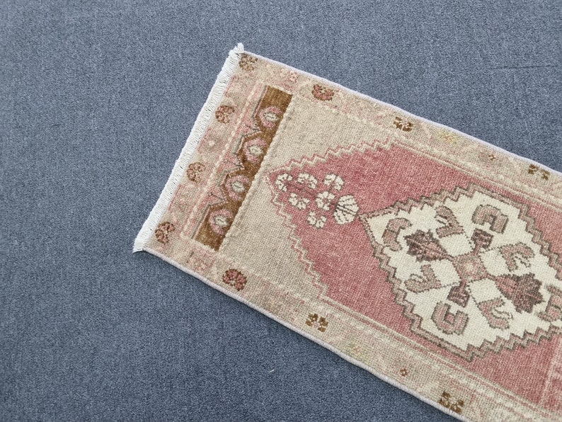 May include: A pink and beige patterned rug with a fringed edge. The rug has a traditional design with floral motifs.