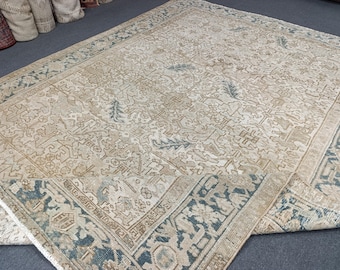 May include: A large, rectangular area rug with an intricate, faded pattern in beige, brown, and teal. The rug features a detailed border and a central design with floral and geometric elements, suitable for home decor.