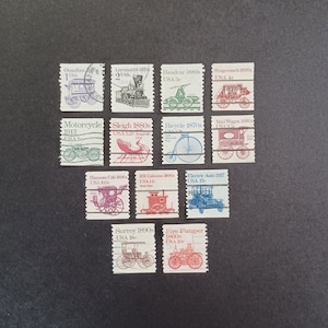 Op de afbeelding: Een verzameling van 12 vintage postzegels met verschillende vervoersmiddelen uit de 1800s en het begin van de 1900s. De postzegels zijn gerangschikt in vier rijen van drie. Elke postzegel toont een ander vervoersmiddel, waaronder een omnibus, een locomotief, een handkar, een postkoets, een motorfiets, een slee, een fiets, een postwagen, een hansom cab, een goederenwagon, een elektrische auto, een surrey en een brandweerwagen. De postzegels zijn allemaal in goede staat en zijn zorgvuldig bewaard gebleven.