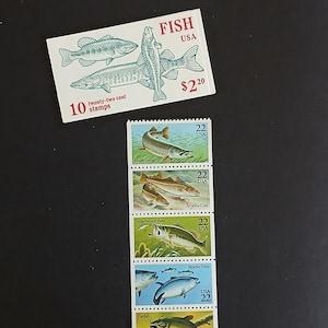 Op de afbeelding: Amerikaanse postzegels met het thema "Vissen USA". De postzegels tonen illustraties van verschillende vissoorten, waaronder muskellunge, largemouth bass, Atlantische kabeljauw, blauwvintonijn en meerval. De tekst op de postzegels luidt "Fish USA".