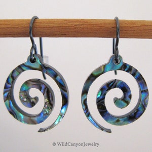 May include: A pair of earrings with a spiral design made from abalone shell. The earrings are a blue, green, and purple iridescent color. The earrings are hanging from black metal hooks.