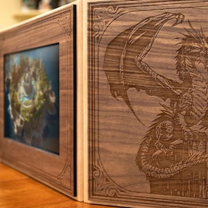 May include: A wooden box with a dragon design engraved on the front. The box has a hinged lid and a small picture frame on the side.
