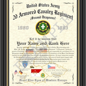 May include: A framed certificate for the United States Army 2d Armored Cavalry Regiment, Second Dragoons, featuring the years 1980-1983, a central unit emblem, a map of Germany and Czechoslovakia, and text detailing service in Fulda.