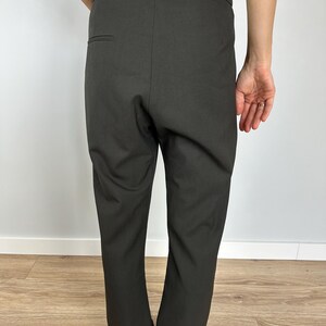 Puede incluir: Pantalones de color carb&oacute;n oscuro con cintura alta y corte entallado. Los pantalones tienen un &uacute;nico bolsillo trasero y un dise&ntilde;o limpio y minimalista. La tela parece ser un material de peso medio, adecuado para diversas ocasiones.