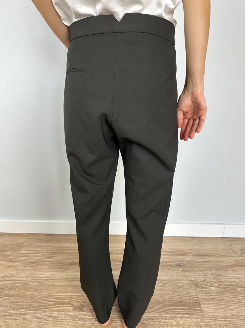 Puede incluir: Pantalones de color carb&oacute;n oscuro con cintura alta y corte entallado. Los pantalones tienen un &uacute;nico bolsillo trasero y un dise&ntilde;o limpio y minimalista. La tela parece ser un material de peso medio, adecuado para diversas ocasiones.