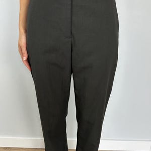 Puede incluir: Pantalones de color carb&oacute;n oscuro con una cintura ancha y un ajuste a medida. Los pantalones tienen un dise&ntilde;o cl&aacute;sico, adecuado para diversas ocasiones. La tela parece ser un material liso y tejido.