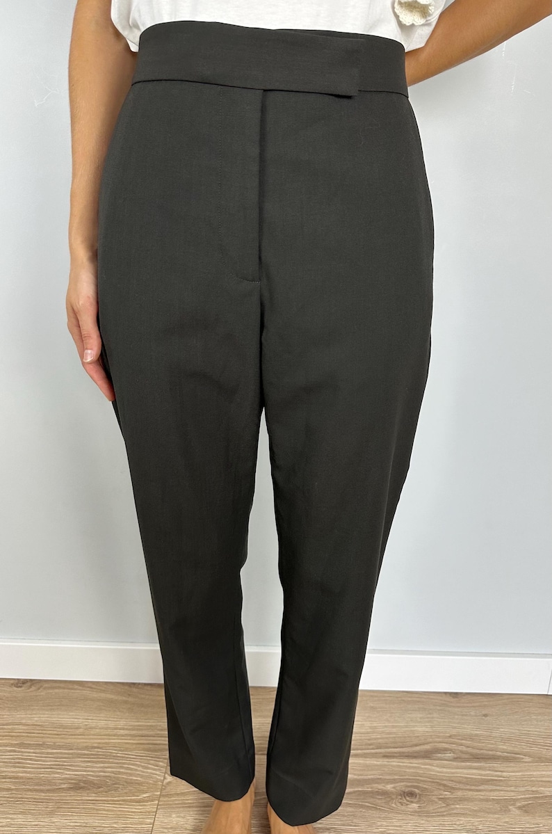Puede incluir: Pantalones de color carb&oacute;n oscuro con una cintura ancha y un ajuste a medida. Los pantalones tienen un dise&ntilde;o cl&aacute;sico, adecuado para diversas ocasiones. La tela parece ser un material liso y tejido.