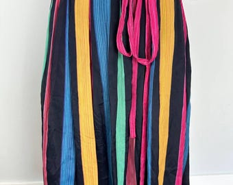 Peut inclure: Une longue jupe noire à rayures verticales colorées. La jupe a une ceinture à nouer rose et est faite d'un tissu léger.