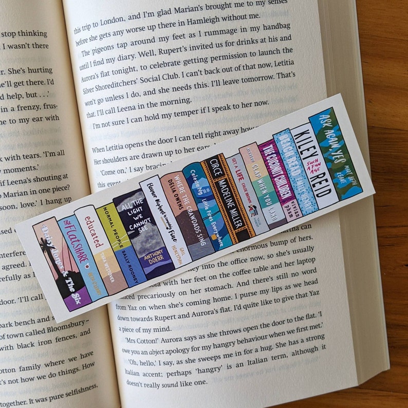 Bookmark depicting the spines of 15 popular books on bookstagram, photographed on an open book