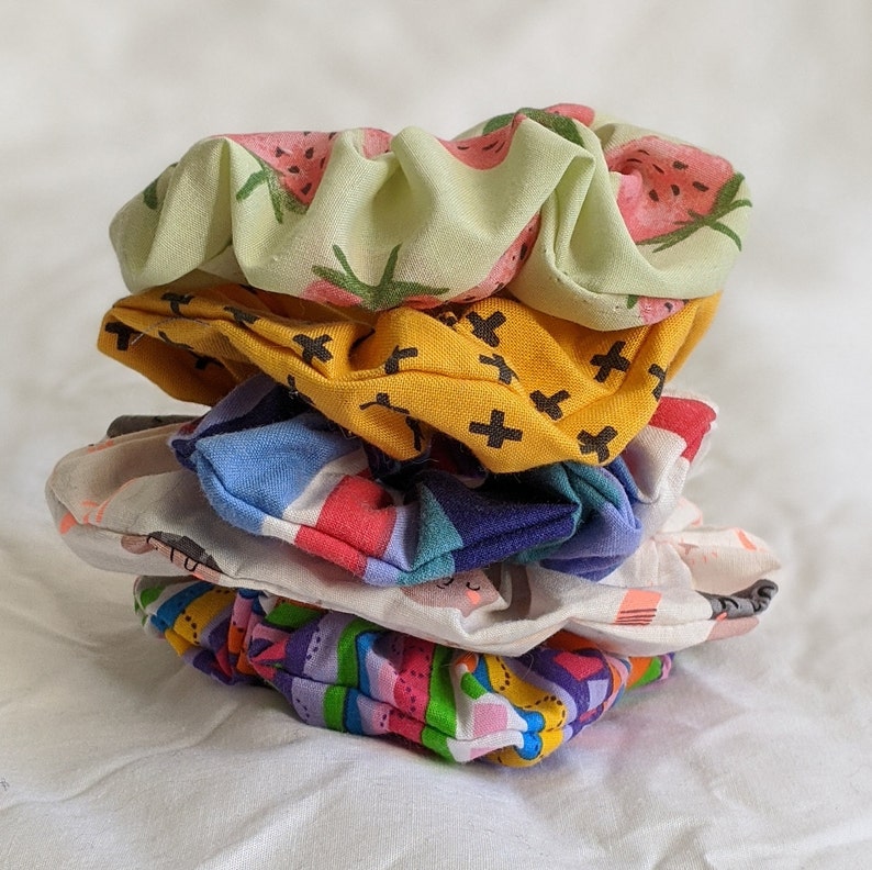 5 colourful scrunchies with various patterns, photographed on a white sheet background