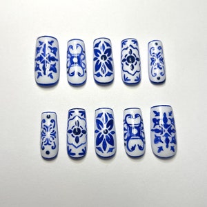 May include: Ten blue and white faux nail tips with a traditional Chinese porcelain design.