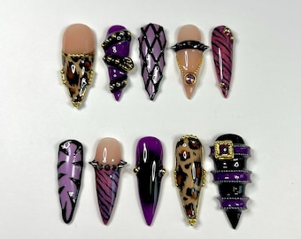 Peut inclure: Un ensemble de dix faux ongles en forme de stylet présentant des motifs variés, notamment des imprimés léopard, des rayures tigrées violettes, des treillis noirs, des clous dorés, des chaînes et une boucle. Palette de noir, violet, or et nude.