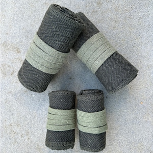May include: Four black and green fabric rolls with a herringbone pattern. Each roll is tied with a green ribbon.