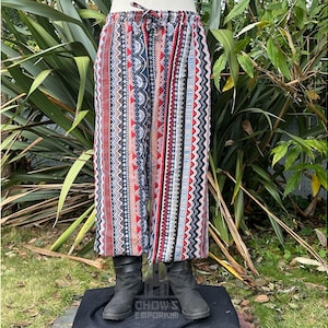 May include: A pair of wide-leg pants with a colorful geometric pattern in shades of red, blue, and white. The pants have a drawstring waist and a relaxed fit.