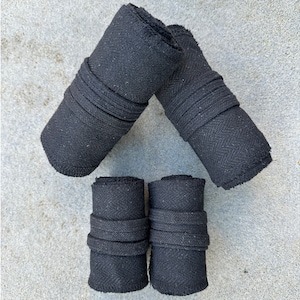 May include: Four black fabric rolls, two larger and two smaller, with a textured surface. The rolls are arranged in a triangular shape.