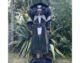 May include: A detailed costume featuring a dark green and black coat with fur accents, leather detailing, and a wide belt. The costume includes a hood, shoulder armour, and matching gauntlets. The boots are black, and the outfit is displayed on a mannequin.