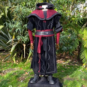 Dark King LARP costume set for nobles, elves & alchemists. Includes black suede waistcoat, layered faux leather hood, wool tunic, hero/ Viking pants, buffalo leather belt, arm wraps & wool sash. Ideal for Ren Faire, cosplay & medieval fantasy events.