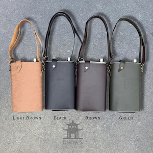 May include: Four leather flask carriers in light brown, black, brown, and green, each with a matching shoulder strap. The flasks are cylindrical with a metal top and white stitching. The text "LIGHT BROWN", "BLACK", "BROWN", and "GREEN" are below each flask.