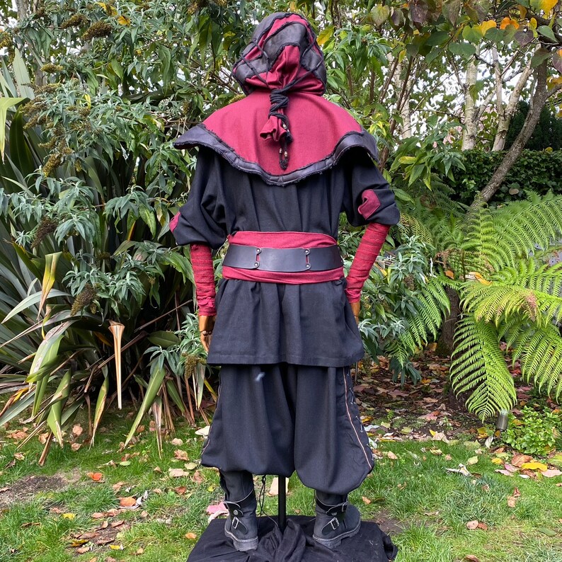 Dark King LARP costume set for nobles, elves & alchemists. Includes black suede waistcoat, layered faux leather hood, wool tunic, hero/ Viking pants, buffalo leather belt, arm wraps & wool sash. Ideal for Ren Faire, cosplay & medieval fantasy events.