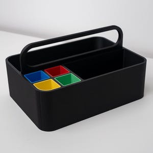 Könnte beinhalten: Ein schwarzer Organizer mit Griff, mit vier farbigen Fächern: blau, gelb, rot und grün. Der Organizer ist rechteckig mit abgerundeten Ecken und für die Aufbewahrung konzipiert.