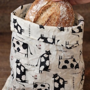 May include: A set of three ceramic mugs with a speckled, cream-colored glaze. Each mug features a different hand-painted design: a blue and green leaf, a yellow and orange flower, and a red berry sprig.