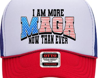May include: A white and red trucker hat with the text "I AM MORE MAGA NOW THAN EVER" in blue and red. The hat has a blue mesh back and a red brim. The hat has a small tag that says "OTTO".