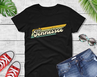 Könnte beinhalten: Schwarzes T-Shirt mit einem Vintage-Grafik des Bundesstaates Tennessee in Gelb, Grün und Blau.