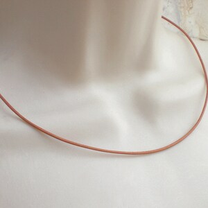 May include: A simple brown leather cord necklace. The cord is thin and smooth, and it is perfect for layering with other necklaces.