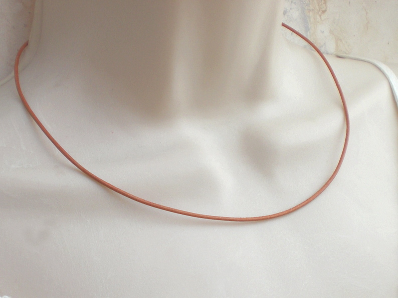 May include: A simple brown leather cord necklace. The cord is thin and smooth, and it is perfect for layering with other necklaces.