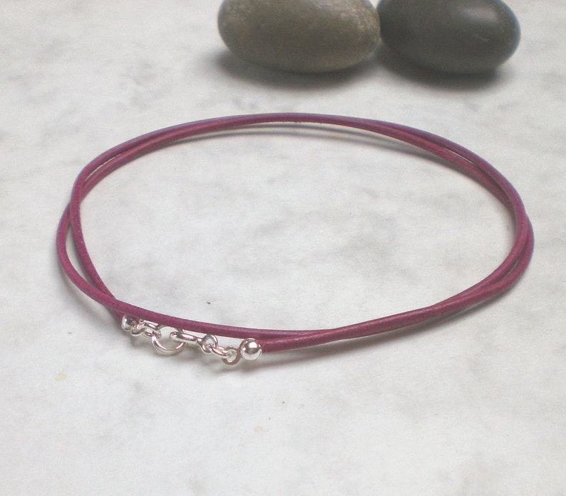 May include: A double-strand leather cord necklace in a deep purple color with a silver clasp and two silver beads.