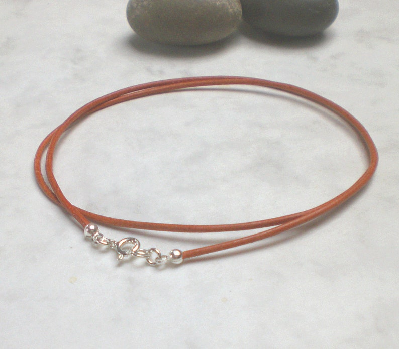May include: A brown leather cord necklace with a silver clasp. The cord is about 18 inches long.