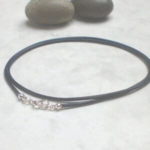 May include: A dark blue leather cord necklace with a silver clasp and two silver beads.