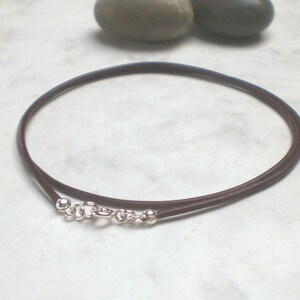 May include: A brown leather cord necklace with silver clasps and beads.