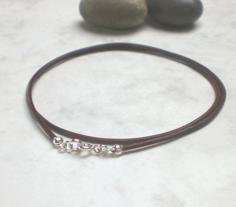 May include: A brown leather cord necklace with silver clasps and beads.