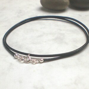 May include: A black leather cord necklace with silver ball end caps and a silver lobster clasp.
