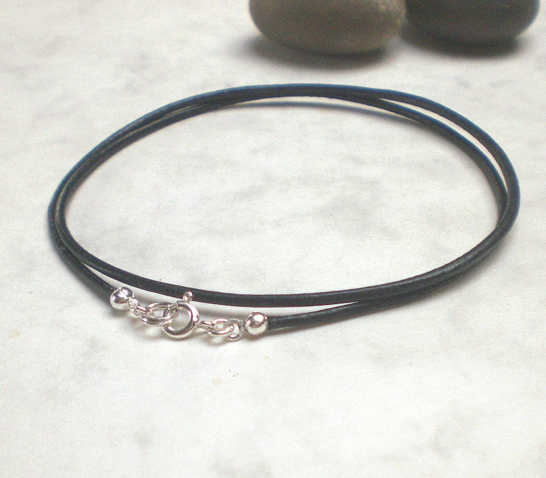 May include: A black leather cord necklace with silver ball end caps and a silver lobster clasp.