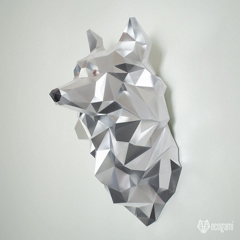 Peut inclure: Une sculpture de t&ecirc;te de loup en papier argent&eacute; avec un design g&eacute;om&eacute;trique. La sculpture est faite de papier pli&eacute; et a une finition m&eacute;tallique brillante.
