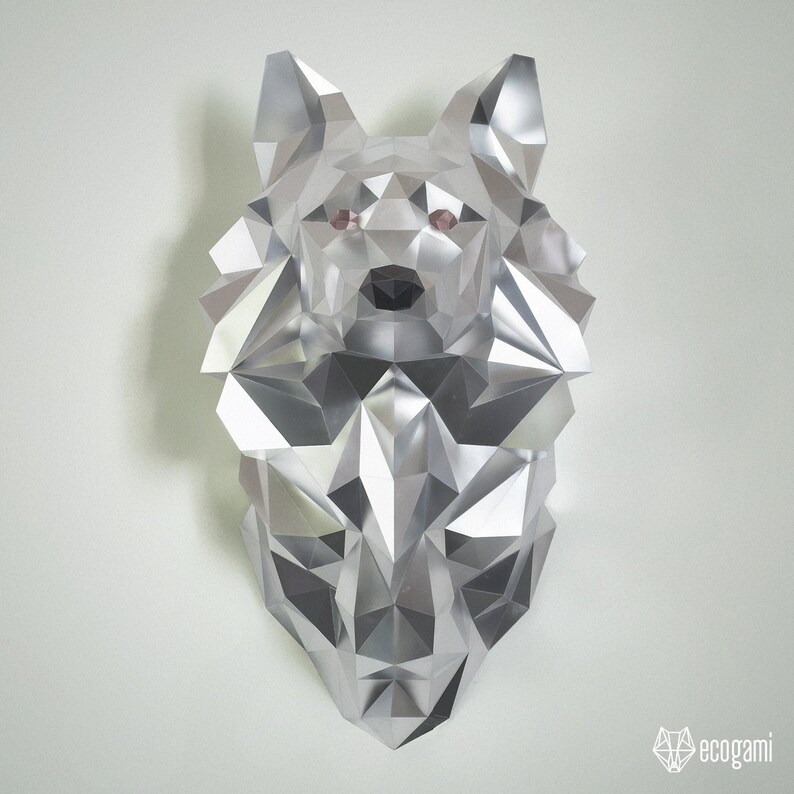Peut inclure: Une sculpture de t&ecirc;te de loup en origami argent&eacute;e avec un design g&eacute;om&eacute;trique. Les yeux du loup sont roses.