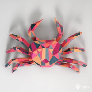 May include: A colorful papercraft crab with a geometric design. The crab is made of pink, orange, red, and gray paper. The crab is a 3D model and is a popular craft project.