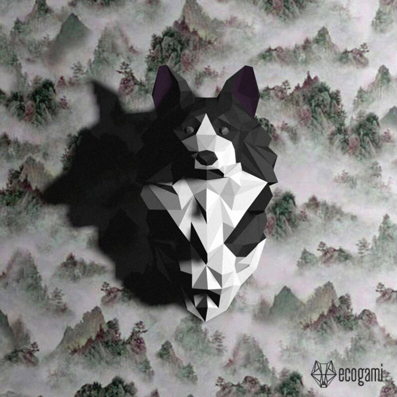 Peut inclure: Un mod&egrave;le en papier origami de la t&ecirc;te d'un chien, en noir et blanc. Le chien a un visage blanc et des oreilles, un corps et une queue noirs. L'arri&egrave;re-plan est une image floue d'un paysage montagneux.