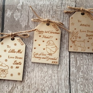 May include: Three wooden Christmas gift tags with twine. The tags are decorated with a reindeer, an owl, and a bird. The tags have the year 2019 and personalized messages.