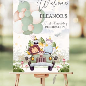 Könnte beinhalten: Willkommen zur ersten Geburtstagsfeier von Eleanor Schild mit einer Aquarell-Illustration eines grünen Jeeps mit Tieren, darunter ein Löwe, ein Zebra, ein Elefant und ein Affe, die durch einen Dschungel mit grünen und rosa Ballons im Hintergrund fahren.