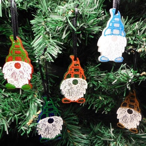 May include: Six colorful gnome ornaments with plaid hats and white beards hanging on a green Christmas tree.