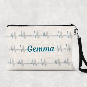 May include: A white canvas makeup bag with a black zipper and a black strap. The bag has a repeating pattern of blue heartbeats and the name "Gemma" in blue cursive lettering.