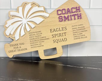May include: Wooden cheerleading-themed plaque with a megaphone shape and a pom-pom design. The plaque features the text "Coach Smith," "Eagles Spirit Squad," and the names of team members. It also includes the phrase "Thank you for a great season."