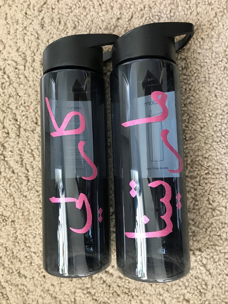 May include: Two black water bottles with pink lettering. The lettering on the left bottle says "J.J." and the lettering on the right bottle says "J.J. mac".